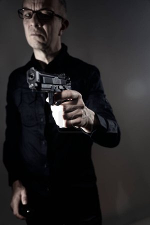 Téléchargez les photos : Spy thriller mafia patron assasin portrait photo en costume tenant pistolet. - en image libre de droit