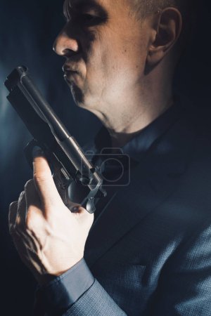 Téléchargez les photos : Spy thriller mafia patron assasin portrait photo en costume tenant pistolet. - en image libre de droit