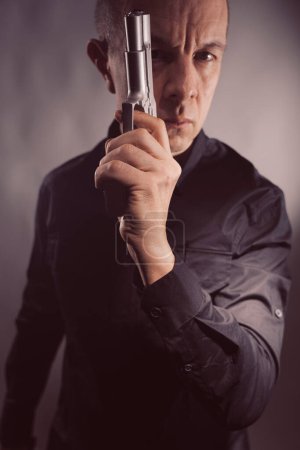 Téléchargez les photos : Mercenaire tueur à gages espion assassin détective avec pistolet portrait studio photo. - en image libre de droit