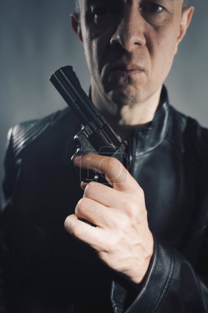 Téléchargez les photos : Veste en cuir noir tueur détective tueur espion tueur assassin avec pistolet portrait photo. - en image libre de droit