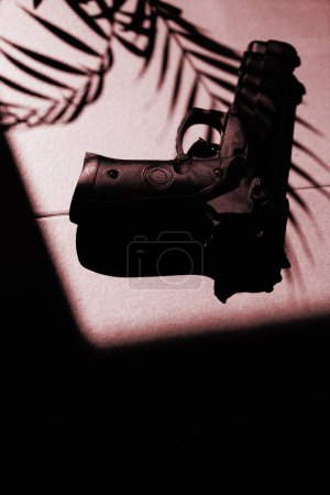 Téléchargez les photos : Spy thriller livre couverture conception pistolet gun.on sol avec des ombres de palmiers tropicaux - en image libre de droit