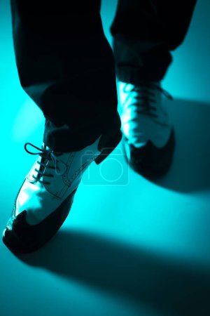 Bailarina masculina bailando en zapatos de salón latinos de jazz con fondo de color liso