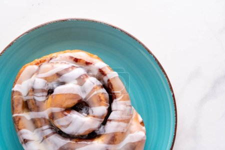 Large gourmet frosted cinnamon roll on marble table