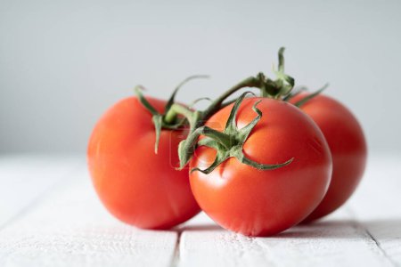 Foto de Tomates maduros de vid roja sobre mesa rústica blanca - Imagen libre de derechos