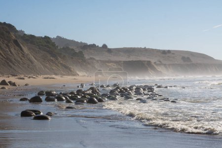 Waves crashing over bowling ball beach rocks in california