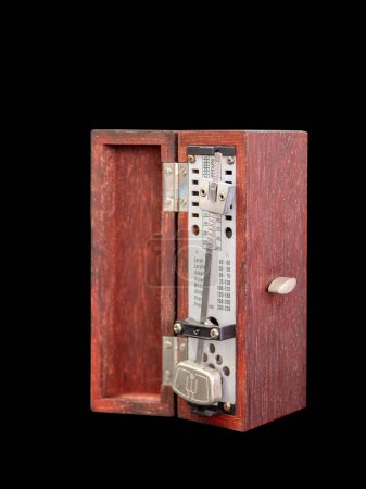 Téléchargez les photos : Un métronome à l'ancienne, en boîte en bois, fond noir, mise au point sélective - en image libre de droit