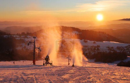 Foto de Ski slope in winter resort with skiers and snow making guns at sunset, Slovakia - Imagen libre de derechos