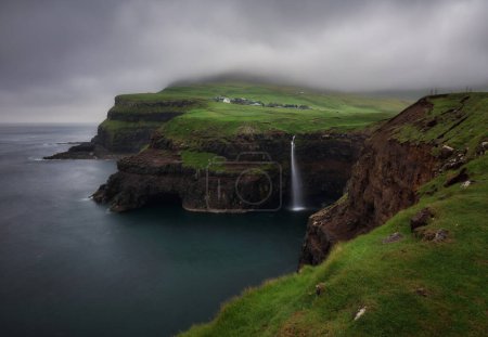 Photo for Gasadalur village and Beautiful waterfall with dark clouds, Vagar, Faroe Islands, Denmark. - Royalty Free Image
