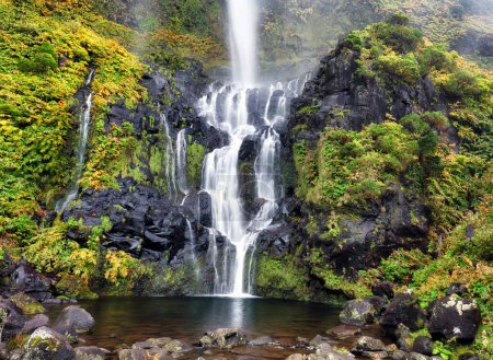 Der Poco do Bacalhau Wasserfall auf der Azoren-Insel Flores. Grüne Hügel und Felder. Sonnenscheindauer.