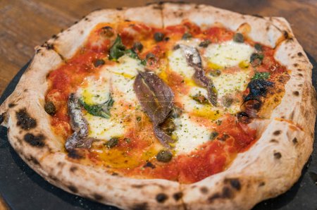 Hausgemachte neapolitanische Pizza mit Sardellen, Oliven und Mozzarella.