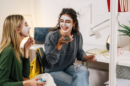 Photo for Teenager friends having fun while applying cosmetic cream on face - Royalty Free Image