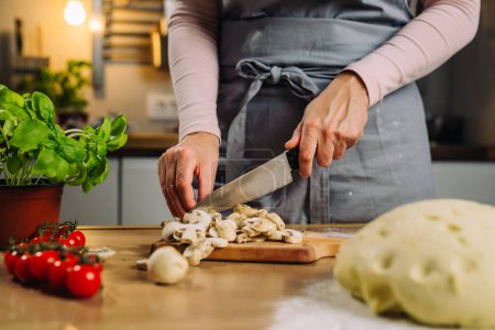 Téléchargez les photos : Gros plan de femme coupe champignon à l'aide d'un couteau dans la cuisine de la maison - en image libre de droit