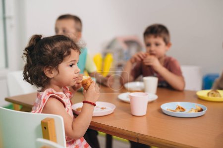 Photo for Young girl eats lunch in kindergarten - Royalty Free Image