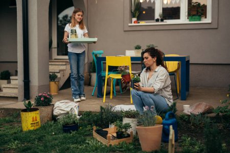 Photo for Mom an daughter work in the garden with a fresh beverage - Royalty Free Image