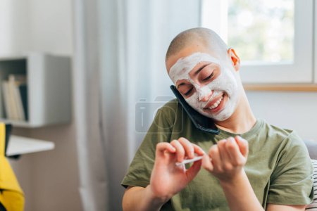 Foto de Adolescente limpia sus uñas con una máscara en la cara - Imagen libre de derechos