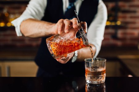 barman verse un cocktail dans un verre