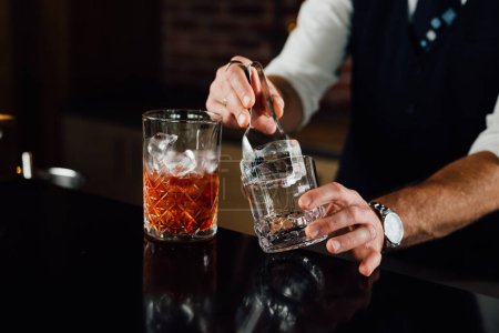 Photo for Close up shot of a bartender putting ice and preparing a cocktail - Royalty Free Image