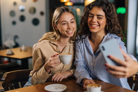 Foto de Dos mujeres jóvenes toman fotos en un café - Imagen libre de derechos