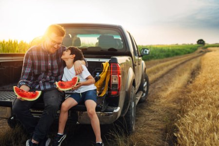 Téléchargez les photos : Fils et papa embrasser sur le camion et manger pastèque - en image libre de droit