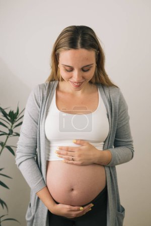 Téléchargez les photos : Femme enceinte regarde son ventre - en image libre de droit
