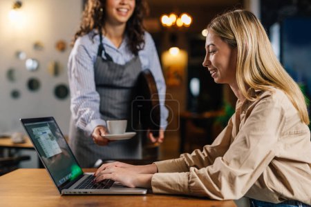 Photo for Businesswoman gets her coffee while working in a cafe - Royalty Free Image
