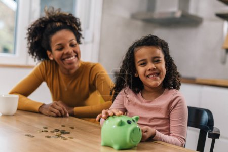 Photo for It's fun for daughter to keep money in a piggy bank - Royalty Free Image