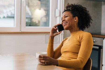 Téléchargez les photos : Adulte femme noire parle au téléphone à la maison - en image libre de droit