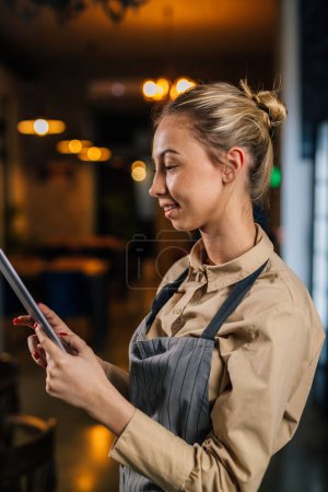 Photo for Profile of a young waitress using a tablet - Royalty Free Image