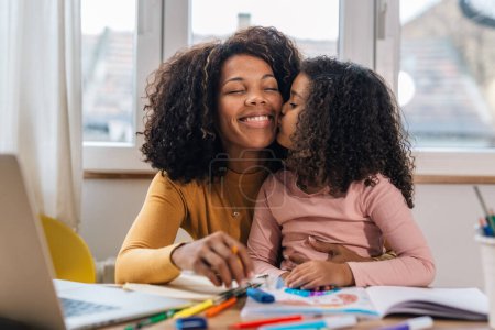 Photo for Mom and daughter working together, loving daughter kisses her mother - Royalty Free Image