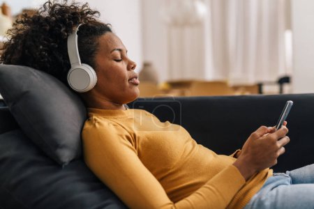 Téléchargez les photos : Femme relaxante avec un peu de musique à la maison - en image libre de droit