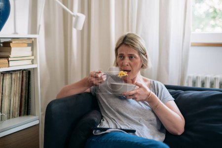 Photo for Mature woman is eating food from a bowl - Royalty Free Image