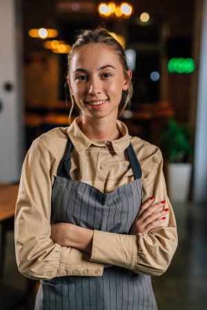 Photo for Waitress wears apron and smiles to the camera - Royalty Free Image
