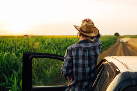 Foto de Granjero mira su campo de maíz una vez más antes de ir en un coche - Imagen libre de derechos