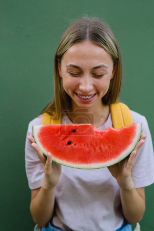 Photo for Cute caucasian woman with braces eats a watermelon - Royalty Free Image