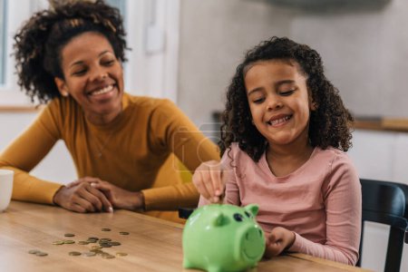 Photo for Daughter is having fun saving money in the piggy bank - Royalty Free Image