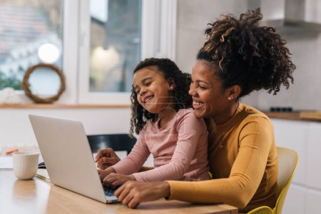 Téléchargez les photos : Mère et fille travaillent ensemble sur ordinateur portable - en image libre de droit