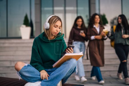Photo for College student is taking a break on a bench in campus - Royalty Free Image