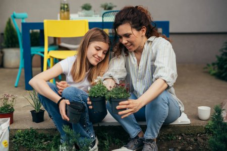 Photo for Mother and daughter are choosing a plant to put in the ground - Royalty Free Image