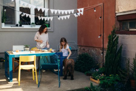 Téléchargez les photos : Mère et fille prennent le petit déjeuner dans la cour arrière - en image libre de droit