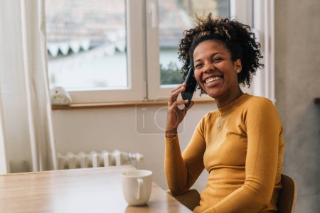 Téléchargez les photos : Heureuse femme afro-américaine a une conversation joyeuse au téléphone - en image libre de droit