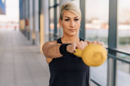 Téléchargez les photos : Front view of a middle aged woman training in a gym with weights - en image libre de droit