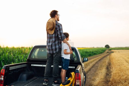 Téléchargez les photos : Père et fils sont montés dans le camion et regardent les champs au loin - en image libre de droit