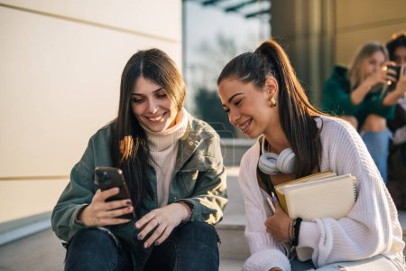 Foto de Dos estudiantes universitarios alegres están mirando el teléfono - Imagen libre de derechos