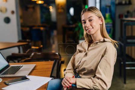 Foto de Joven mujer de negocios está sentada en un café y mirando a la cámara - Imagen libre de derechos