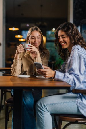 Téléchargez les photos : Deux jeunes femmes passent du temps ensemble dans un café - en image libre de droit