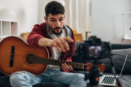 Photo for Musician is recording himself play the guitar with a camera - Royalty Free Image