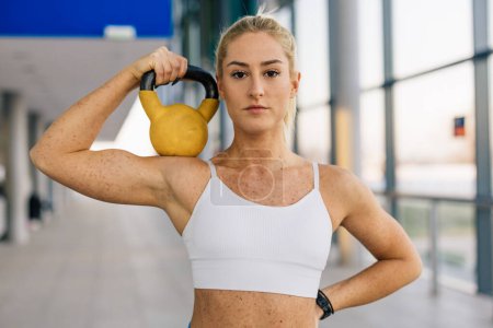 Photo for Portrait of a blond European woman holding a weight in the gym - Royalty Free Image