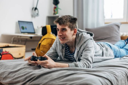 Téléchargez les photos : Teenage boy plays video game at home - en image libre de droit