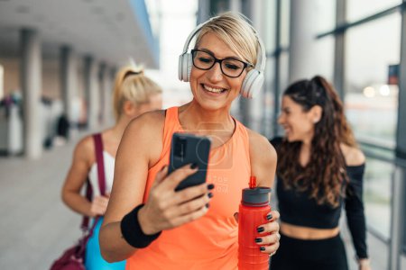 Photo for Front view of a blonde middle-aged woman having a video call in the gym - Royalty Free Image