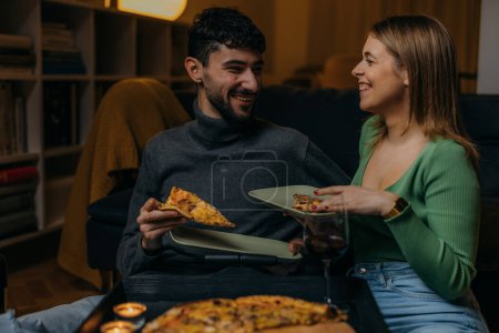 Photo for Young couple is having pizza together at home - Royalty Free Image